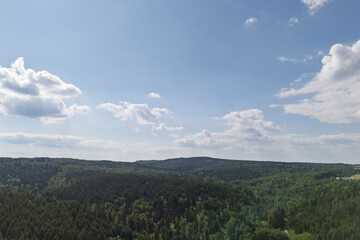 Scenic view of lush green hills under a bright blue sky with fluffy clouds. A perfect depiction of nature's beauty and tranquility.