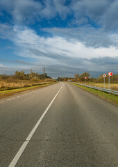 A long, empty road with a few trees in the background
