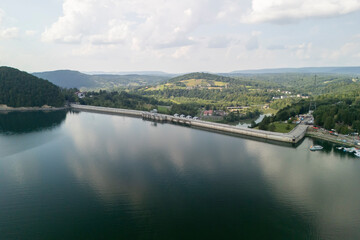A scenic aerial view of a tranquil reservoir, surrounded by lush green hills under a bright sky. Perfect for nature lovers and outdoor enthusiasts.