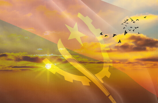 Waving the flag of Angola against the background of a sunset or sunrise. Angola flag for Independence Day. The symbol of the state on wavy fabric.