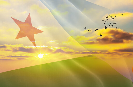 Waving the flag of Djibouti against the background of a sunset or sunrise. Djibouti flag for Independence Day. The symbol of the state on wavy fabric.