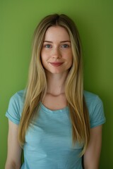 Obraz premium Young Woman with Blonde Hair in Blue T-Shirt Against a Green Background for Lifestyle Imagery