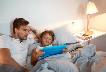 Obraz premium Night, tablet and dad with kid in bed for streaming movies, film or series together in family home. Relax, single parent or boy child with father on touchscreen technology for playing games or ebook