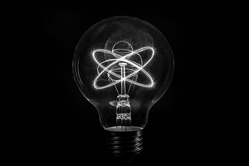 Light bulb filament is glowing brightly, taking the form of an atom symbol, representing scientific innovation and discovery