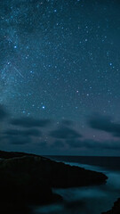 Starry night above the Atlantic Ocean and Loop Head rock formations. County Clare. Long exposure photograph.