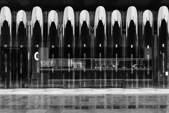 Black and white photo of a modern building facade with reflective surfaces and symmetrical design