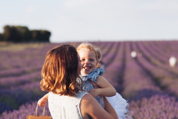 Happy and smiling mother and a little adorable cute blond daughter are hugging and kissing in a...