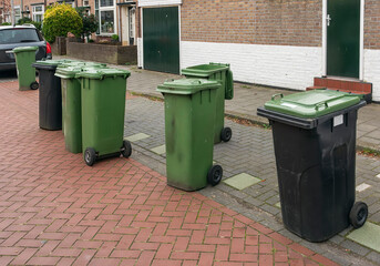 plastic waste bins are scattered outside on the street in a residential area