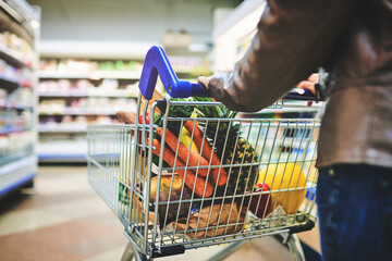 Woman, trolley and hands for browsing in supermarket, goods discount and shelves for deal. Female person, sale and shop for options on offer, retail aisle and customer for grocery choice in store