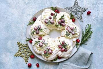 Christmas meringue cake Pavlova with cranberry and rosemary . Top view with copy space.