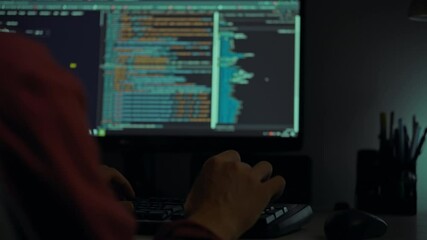 A person is engaged in coding at night, with a computer screen displaying vibrant lines of programming text and graphical data. The atmosphere is dim and focused on the work