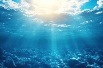 Obraz premium Sunlight filtering through the ocean surface creates a tranquil underwater scene in clear blue waters