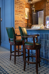 cozy vintage interior of the cafe restaurant with blue walls, wooden floors and brickwork. blue and red chairs are arrenged around tables. natural lighting and lamps.