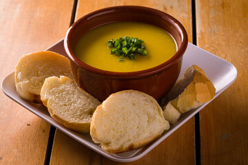 Delicious Pumpkin Soup Served with Bread on Wooden Table
