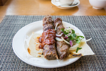 kebab lula served on a plate with onions and pita bread and sauce in a restaurant