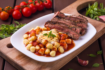 Delicious Grilled Steak with Gnocchi and Tomato Sauce on White Plate