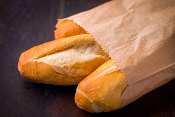 Freshly Baked Baguettes in Brown Paper Bag on Rustic Dark Surface