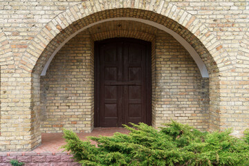 A large wooden church gate in a medieval church. The Gothic building is made of red brick. Decorative elements of the ancient temple.