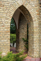 The exterior of the old Gothic red brick church. Arched arches and windows. Green spaces around the church.
