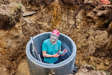 Builder face and safety glasses covered in cement dust after cutting concrete ring with diamond wheel.