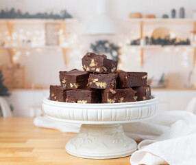 Homemade Chocolate Peacn Fudge on a White Pedestal in Kitchen Decorated for Christmas