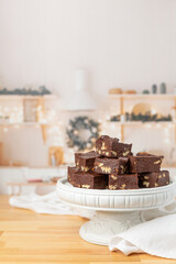 Homemade Chocolate Peacn Fudge on a White Pedestal in Kitchen Decorated for Christmas