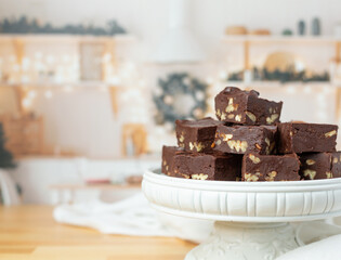 Homemade Chocolate Peacn Fudge on a White Pedestal in Kitchen Decorated for Christmas