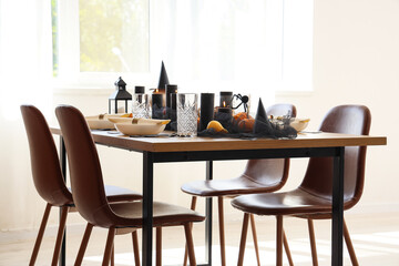 Festive table setting with pumpkins and burning candles for Halloween party in light room