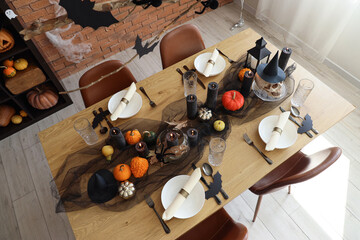 Festive table setting with pumpkins and burning candles for Halloween party at home