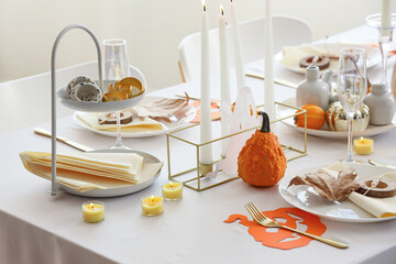 Festive table setting with pumpkins and burning candles for Halloween party