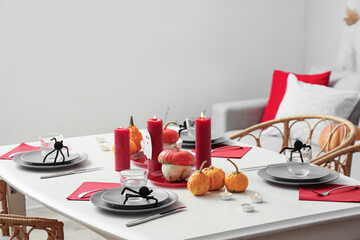 Festive table setting with spiders, burning candles and pumpkins for Halloween party
