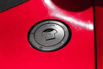 Red sports car fuel cap with push lock, close-up photo