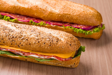 Delicious Baguette Sandwiches With Fresh Ingredients on Wooden Table