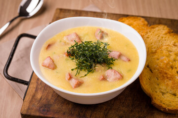 Warm Creamy Soup with Croutons and Fresh Herbs on Wooden Board