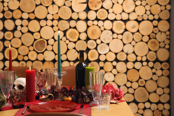 Festive table setting with Halloween skull, burning candles and leaves in dining room
