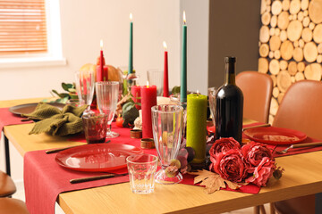 Festive table setting with Halloween decorations, burning candles and leaves