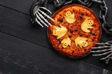 Board with tasty pizza and decorations for Halloween party on black wooden background