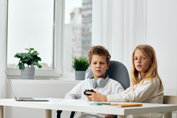 Happy children studying at home using laptops and headphones for online elearning Two siblings, a...