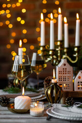 Elegant decor for Christmas family dinner. Center piece with burning candles, vintage chandelier. Zero waste eco-friendly reusable home decoration, fir tree branches. Cozy atmosphere, wooden furniture
