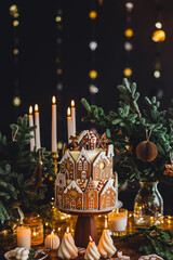 Family holiday celebration. Beautiful traditional homemade gingerbread house. Celebration of Christmas and Happy new year at home. Festive mood, cozy atmosphere, burning candles, fir tree branches