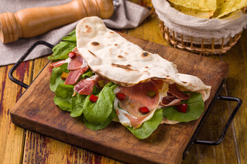 Delicious Fresh Flatbread Sandwich with Ham and Vegetables on Wooden Board