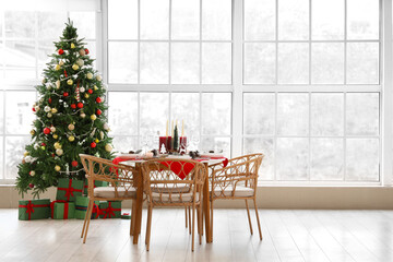 Interior of room with festive dining table and Christmas tree