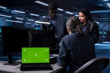 Multiethnic team using green screen screen laptop to check for signs of imminent failure in data...