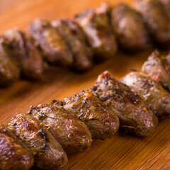 Close-Up Of Grilled Delicious Skewered Chicken Heart On Wooden Board