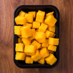 Bright Yellow Polenta Cubes in Black Tray on Wooden Surface