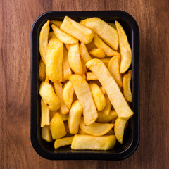 Perfectly Cooked Golden French Fries in a Black Tray on Wooden Table