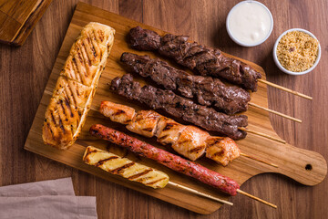 Delicious Grilled Meat Skewers with Sides on Wooden Board