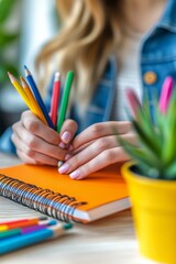 Creative writing session with colorful pencils and an orange notebook on a wooden table