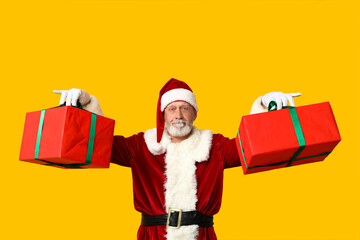 Santa Claus with gift boxes on yellow background