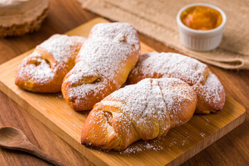 Delicious Freshly Baked Pastries Sprinkled with Powdered Sugar on a Wooden Board